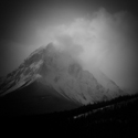 Cloud forming behind snowy peak